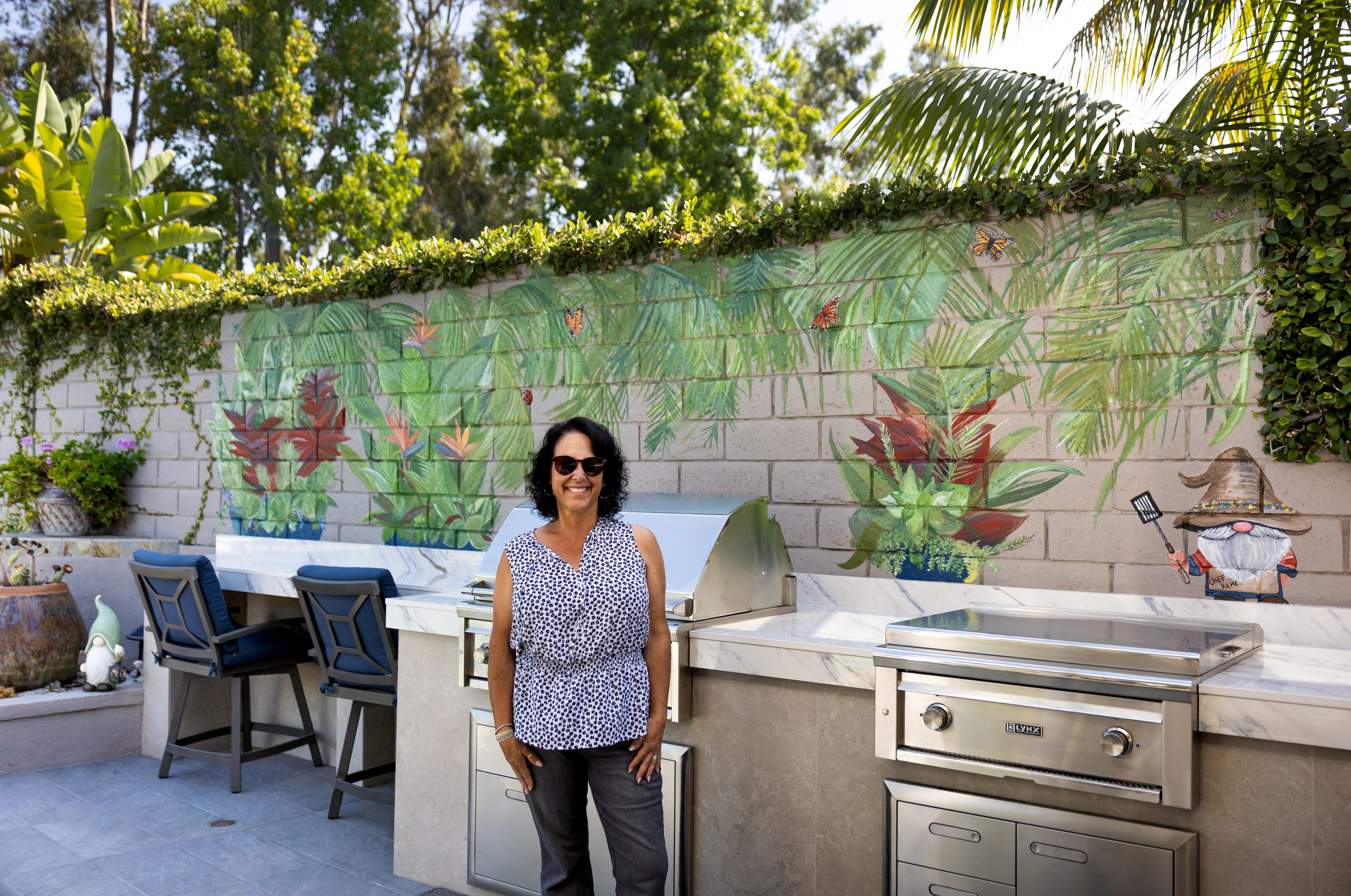 Shannon Ratcliffe posing in front of a tropical outdoor kitchen mural she painted